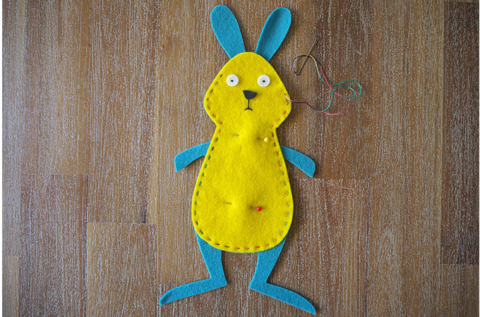 Sewing around the torso of a rabbit soft toy